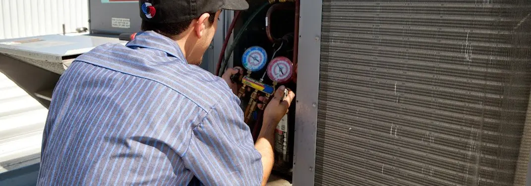HVAC technician servicing a condenser unit in Ira